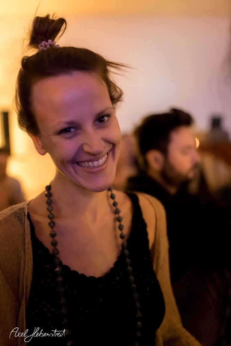 Lächelnde Frau mit lässigem Look in gedämpftem Licht, die eine entspannte Atmosphäre ausstrahlt – © Axel Hebenstreit