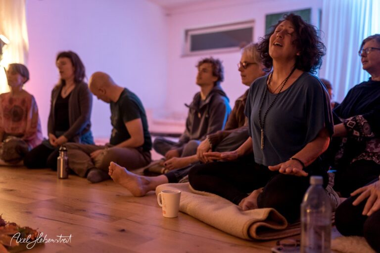 Gemeinsame Meditation in entspannter Atmosphäre, Teilnehmer sitzen auf dem Boden und konzentrieren sich – © Axel Hebenstreit