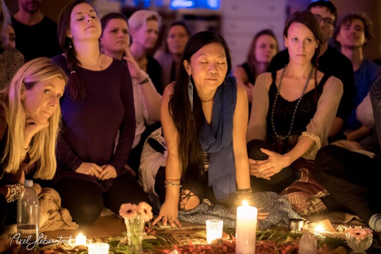 Gruppensitzung mit meditativer Atmosphäre, umgeben von Kerzenlicht und fokussierten Teilnehmern – © Axel Hebenstreit.