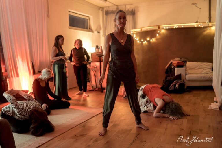 Eine Gruppe von Frauen praktiziert Yoga in einem sanft beleuchteten Raum mit entspannter Atmosphäre – © Axel Hebenstreit