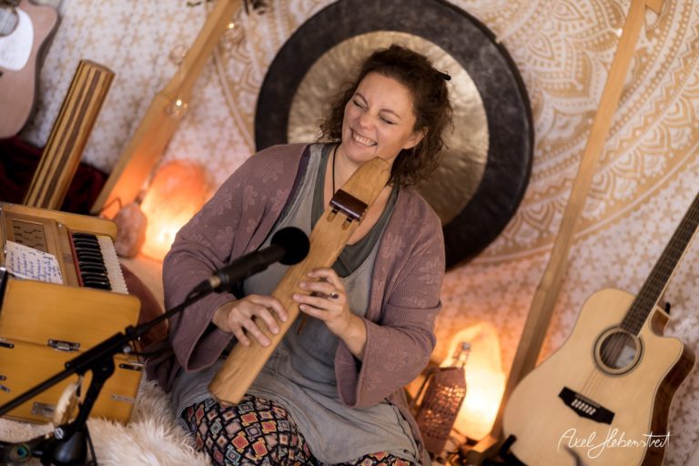 Eine Musikerin spielt glücklich ein Holzblasinstrument in einer stimmungsvollen Umgebung mit sanftem Licht – © Axel Hebenstreit