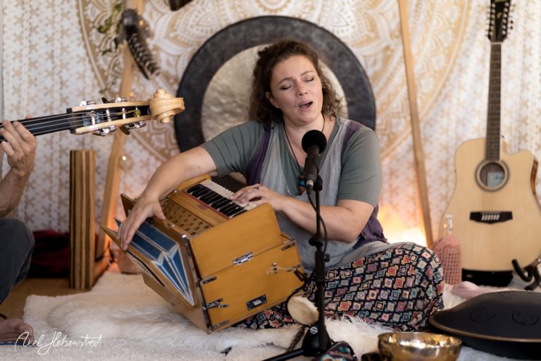 Eine Frau singt und spielt Harmonium während einer entspannten Musiksession in einem bezaubernden Raum – © Axel Hebenstreit