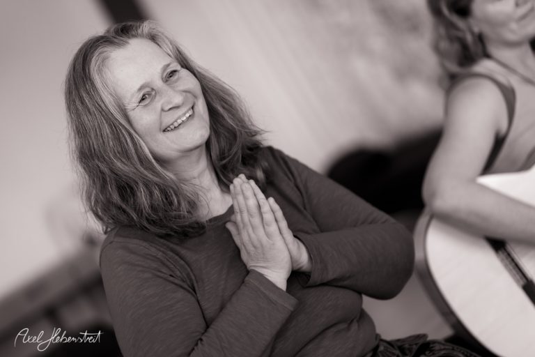 Eine lächelnde Frau mit zusammengelegten Händen, die eine friedliche und meditative Stimmung ausstrahlt – © Axel Hebenstreit