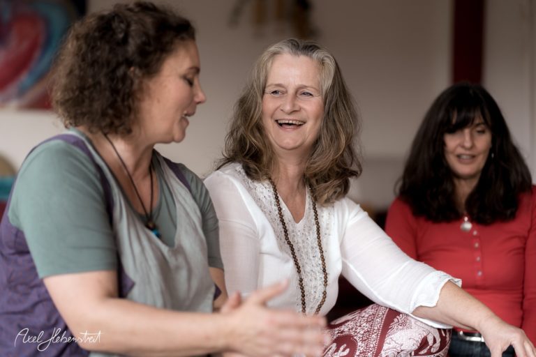 Drei Frauen in entspannter Atmosphäre diskutieren und lächeln in einem hellen Raum – © Axel Hebenstreit.