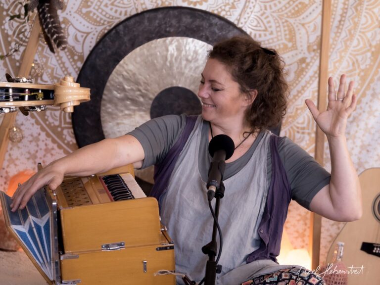 Frau spielt lächelnd Harmonium in entspannter Atmosphäre mit musikalischem Hintergrund – © Axel Hebenstreit