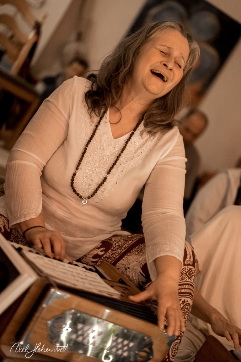 Frauenstimme in Ekstase, während sie an einem Harmonium in einer entspannten, spirituellen Atmosphäre spielt – © Axel Hebenstreit