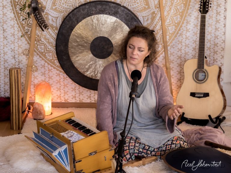 Frau singt am Mikrofon, umgeben von Musikinstrumenten und einer harmonischen, entspannten Atmosphäre – © Axel Hebenstreit