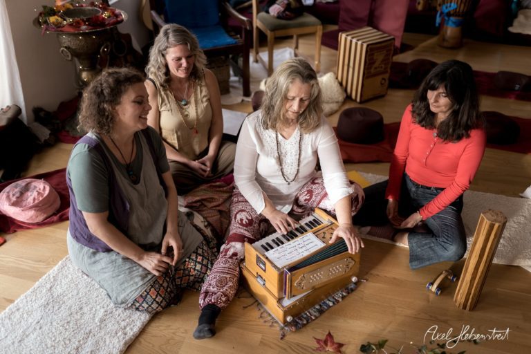 Vier Frauen sitzen auf dem Boden und umringen ein harmonium, während sie gemeinsam musizieren – © Axel Hebenstreit
