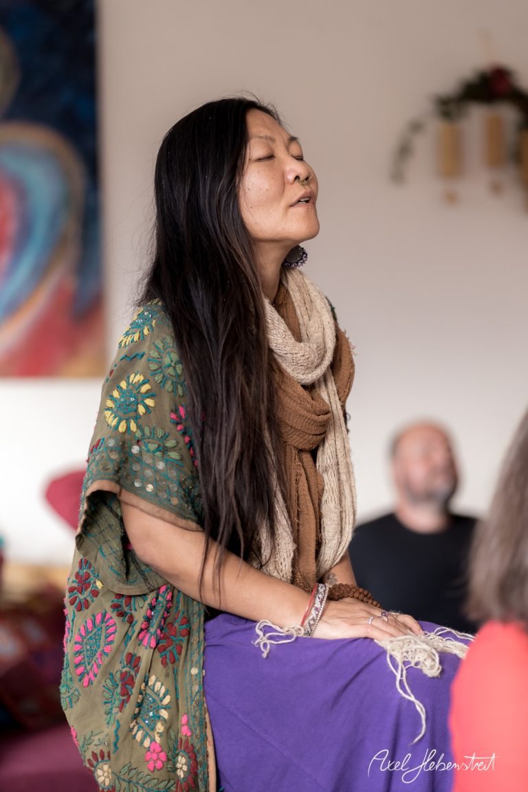 Eine Frau in buntem Gewand meditiert in einer entspannenden Yoga-Umgebung. – © Axel Hebenstreit