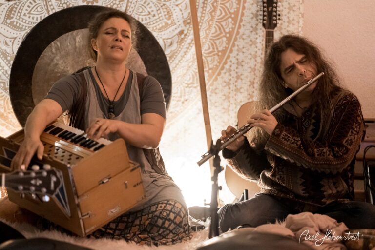 Zwei Musiker in einer entspannten Atmosphäre spielen Harmonium und Flöte, umgeben von warmem Licht – © Axel Hebenstreit.