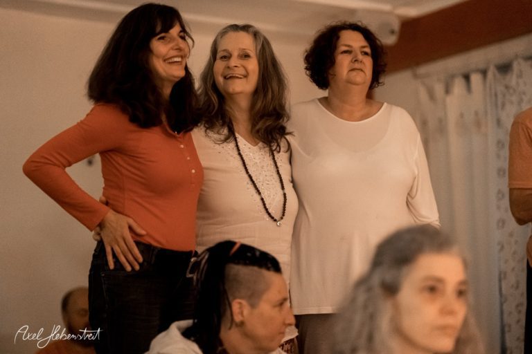 Drei Frauen stehen lächelnd in einer entspannten Atmosphäre bei einem Yoga-Event – © Axel Hebenstreit.