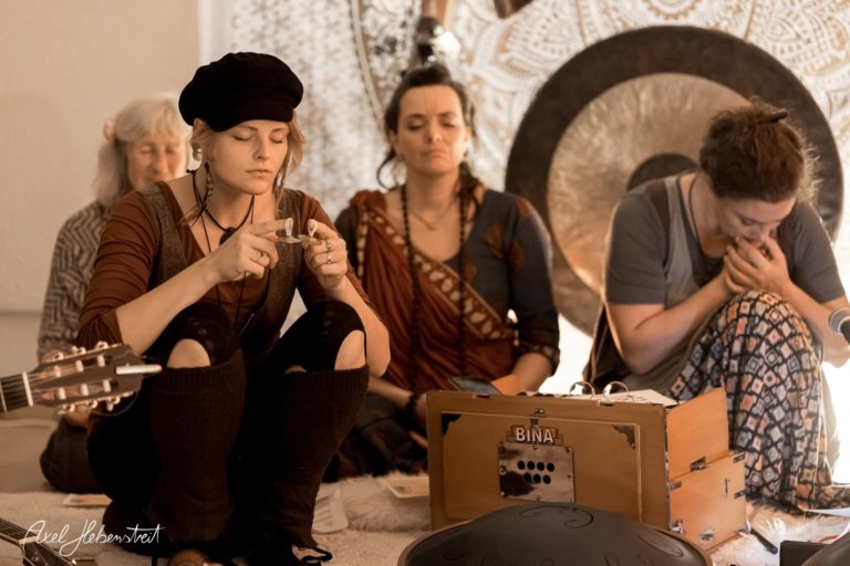 Eine Gruppe von Frauen sitzt in entspannter Atmosphäre und meditiert mit Musikinstrumenten in einem ruhigen Raum – © Axel Hebenstreit