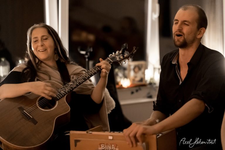 Ein Duo spielt mit Gitarre und Cajón in entspannter Atmosphäre, umgeben von sanftem Licht – © Axel Hebenstreit