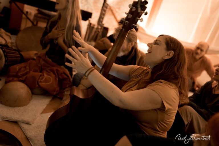 Eine Gruppe Menschen sitzt zusammen und musiziert in entspannter Atmosphäre – © Axel Hebenstreit