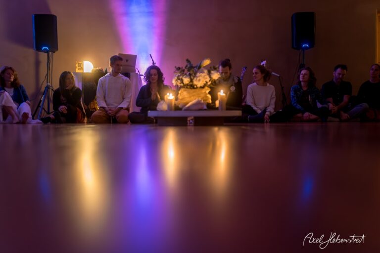 Meditative Atmosphäre bei einer Yogasession mit Kerzenlicht und Musik, Teilnehmer sitzen entspannt auf dem Boden – © Axel Hebenstreit