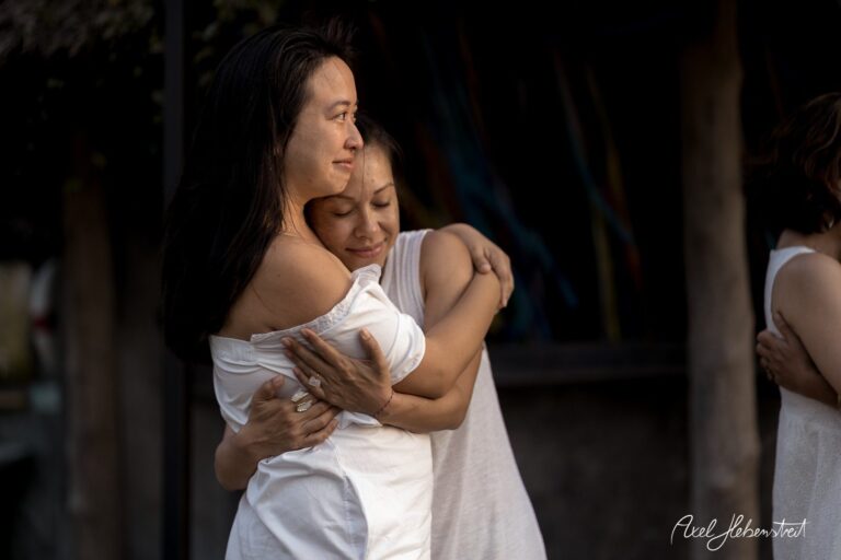 Zwei Frauen umarmen sich liebevoll in einem warmen Licht, was eine intime und emotionale Verbindung zeigt. – © Axel Hebenstreit