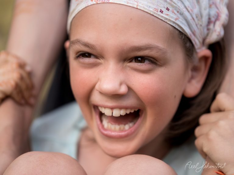 Lachendes Kind mit Stirnband blickt freudig in die Kamera – © Axel Hebenstreit