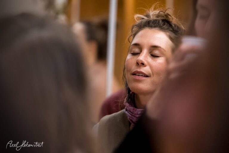 Eine Frau mit geschlossenen Augen genießt einen ruhigen Moment umgeben von einer Menschenmenge – © Axel Hebenstreit