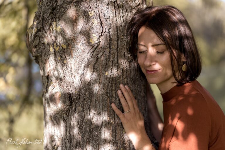 Frau, die an einem Baum lehnt und mit geschlossenen Augen die Natur genießt – © Axel Hebenstreit