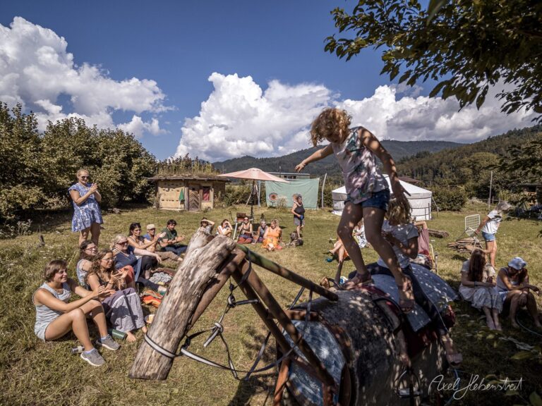 Kinder balancieren auf Baumstamm beim Outdoor-Festival in alpiner Berglandschaft – © Axel Hebenstreit