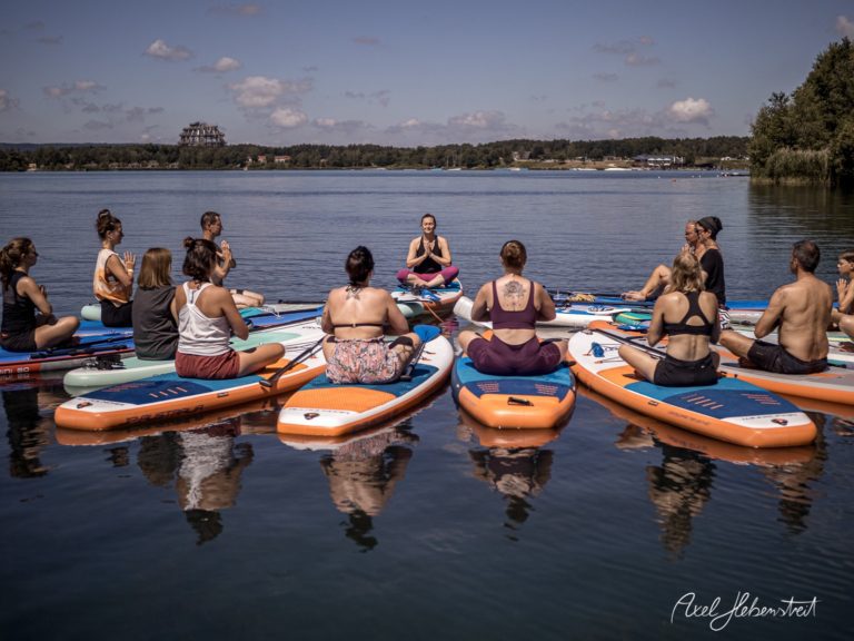 Yoga auf Stand-Up-Paddle-Boards auf einem ruhigen Gewässer in Bayern, umgeben von Natur – © Axel Hebenstreit