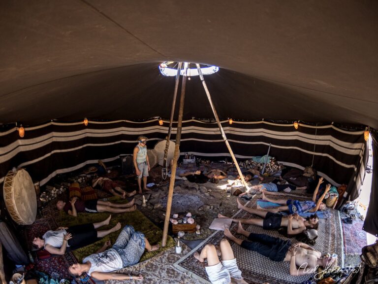 In einem Zelt entspannen Menschen auf Matten, während sanftes Licht durch die Öffnung strömt – © Axel Hebenstreit