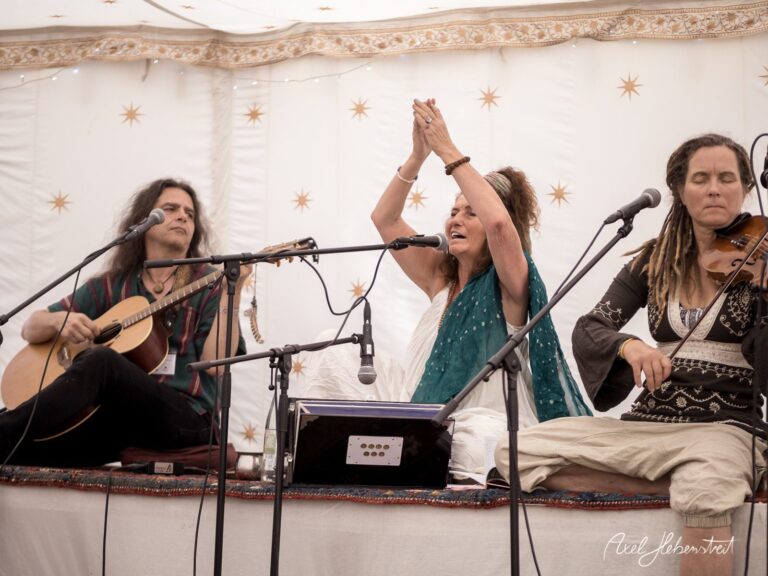Musiker performen in einem bunten Zelt, eine spirituelle Atmosphäre mit Gesang und Instrumenten. – © Axel Hebenstreit