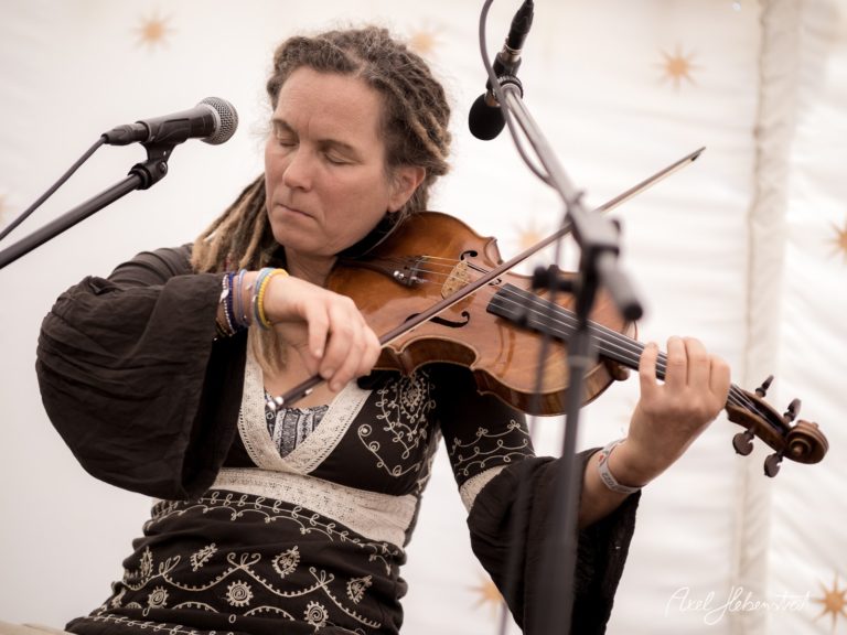 Fidelspielende Künstlerin mit Dreadlocks in einem festlichen Zelt auf einem Konzert – © Axel Hebenstreit