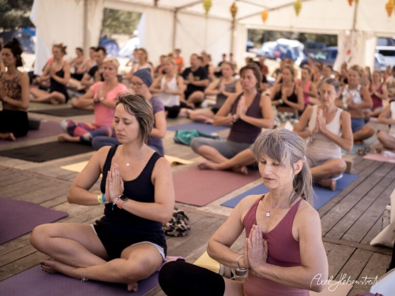 Yoga-Praktizierende in meditativer Haltung während einer Veranstaltung in einem Zelt – © Axel Hebenstreit