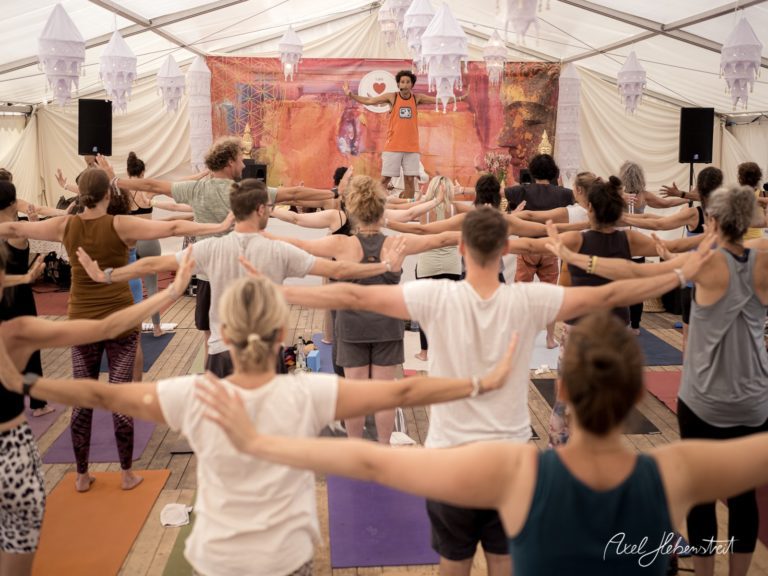 Gruppenyogastunde mit vielen Teilnehmern in einem festlich dekorierten Zelt – © Axel Hebenstreit