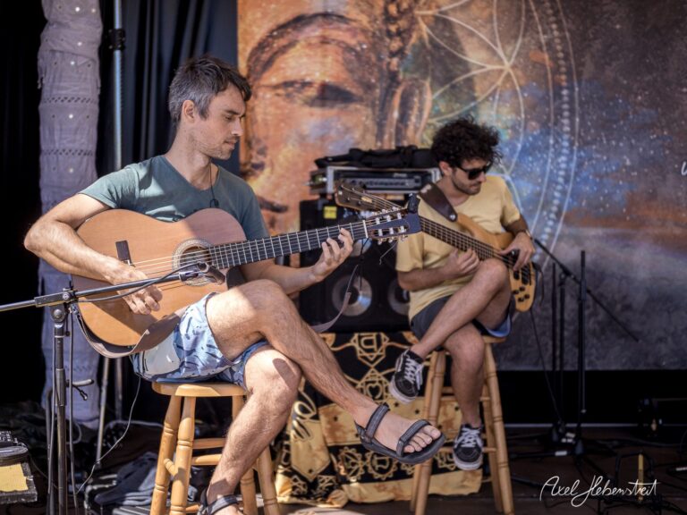 Zwei Musiker spielen akustische Instrumente auf einer Bühne vor einer meditativen Hintergrundgestaltung – © Axel Hebenstreit