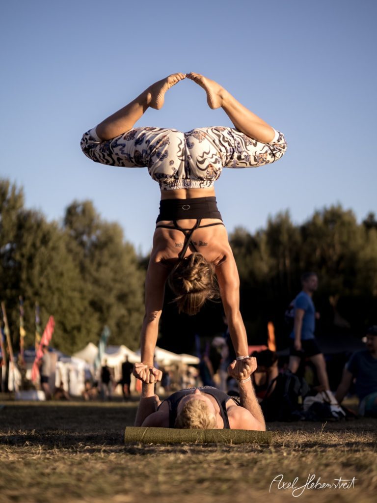 Eine Akrobatin macht eine beeindruckende Balance-Übung auf einem Partner im Freien während eines Festivals – © Axel Hebenstreit
