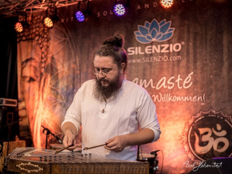 Musiker spielt auf einer Kalimba bei einem Festival, umgeben von stimmungsvollem Licht und tibetischen Elementen – © Axel Hebenstreit