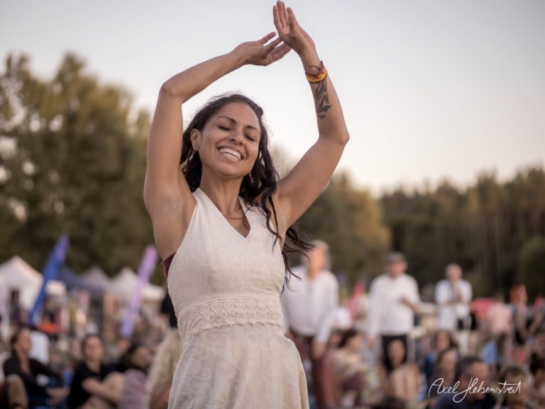 Eine tanzende Frau in einem weißen Kleid genießt die Freude des Festivals im Freien – © Axel Hebenstreit