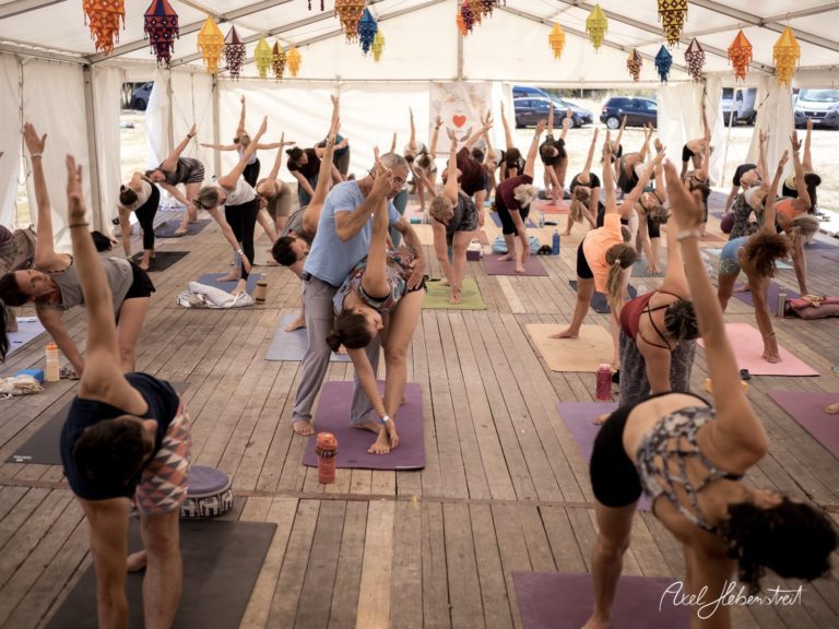 Yoga-Session in einem Zelt, Teilnehmer in verschiedenen Posen, konzentrierte Atmosphäre – © Axel Hebenstreit