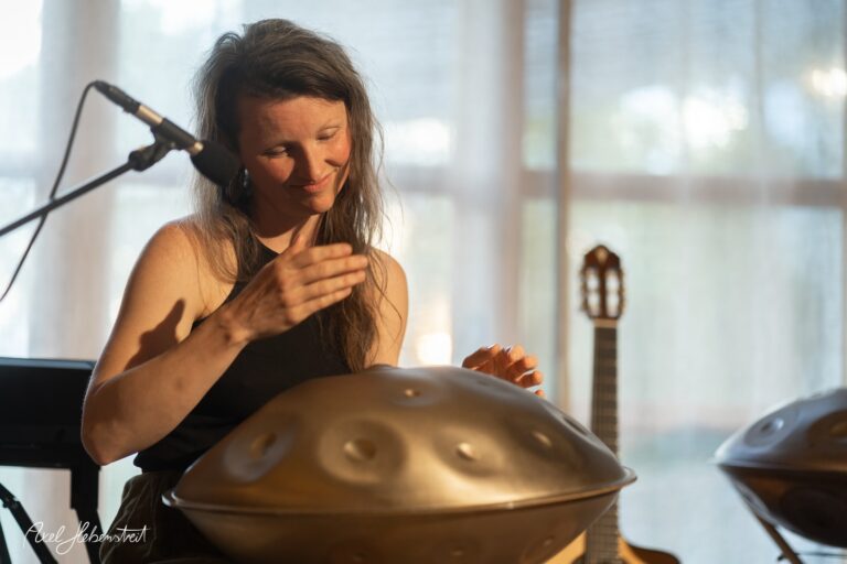 Musikerin spielt konzentriert Handpan während eines intimen Konzertes in hellem Raum