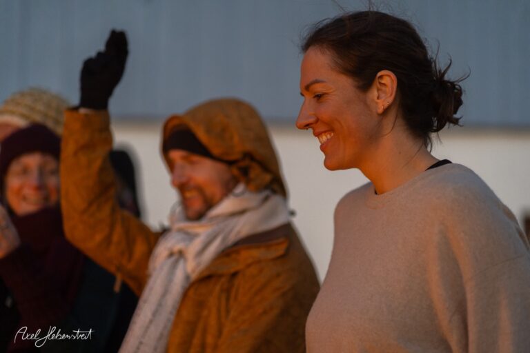 Lachende Frau bei Sonnenuntergang mit Freunden in warmer, goldener Abendstimmung