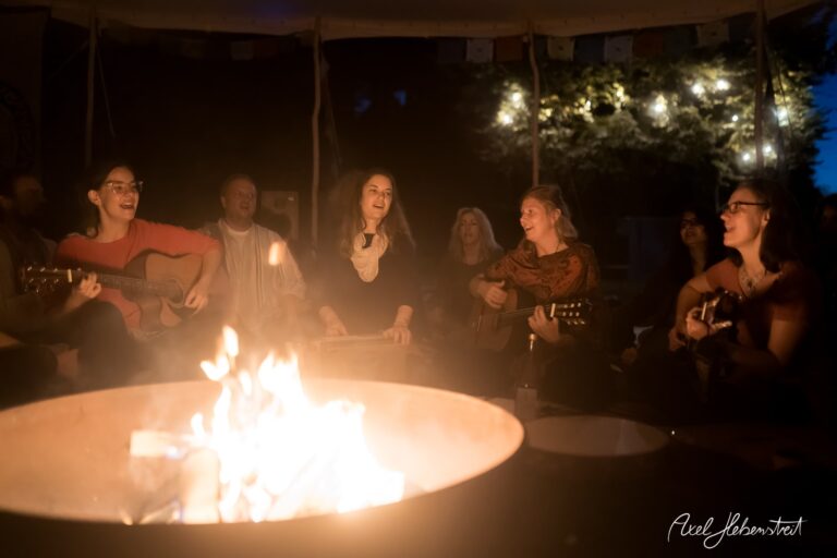 Musikalische Gemeinschaft am Lagerfeuer mit Gitarrenmusik und strahlenden Gesichtern in einem festlichen Ambiente – © Axel Hebenstreit