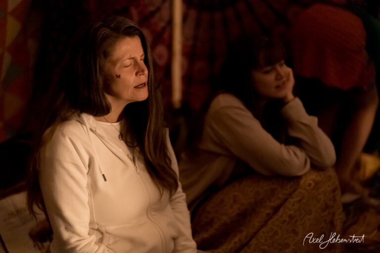 Zwei Frauen in einer entspannten, meditativen Atmosphäre, umgeben von warmem Licht und bunten Tüchern. – © Axel Hebenstreit