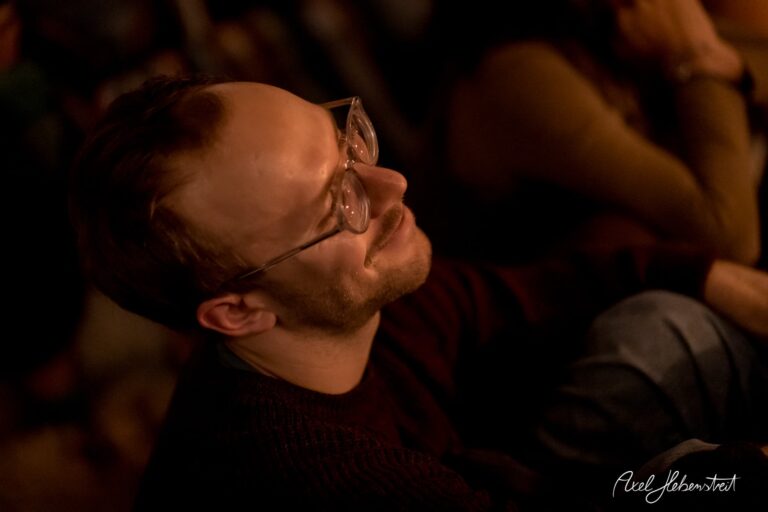 Ein lächelnder Mann genießt lebhaft eine Veranstaltung in entspannter Atmosphäre. – © Axel Hebenstreit