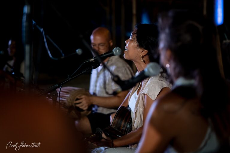 Musikerin singt leidenschaftlich accompanied von zwei Instrumentalisten, in einer lebhaften Konzertatmosphäre – © Axel Hebenstreit