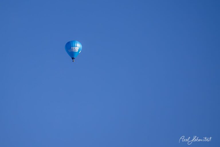 Ein Heißluftballon schwebt sanft am klaren blauen Himmel über Bayern – © Axel Hebenstreit.