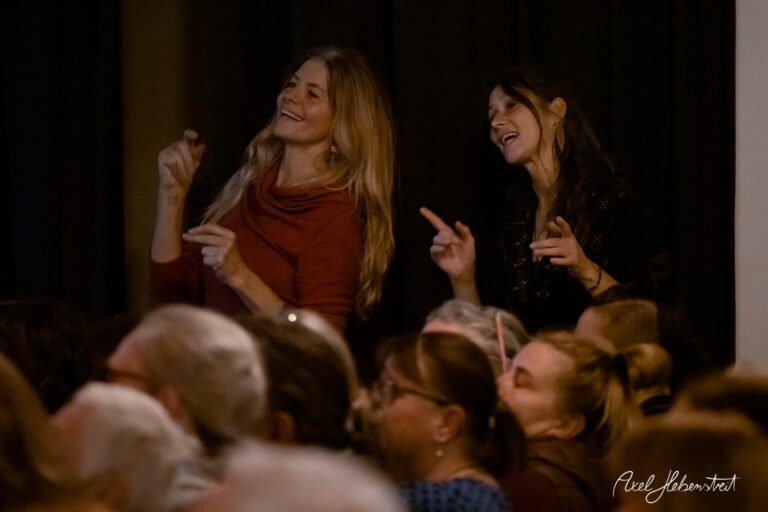 Zwei Frauen tanzen und singen begeistert im Publikum eines Konzerts – © Axel Hebenstreit